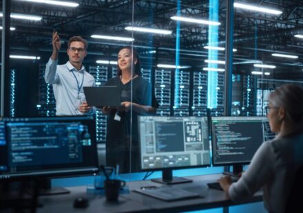 Team of DevOps engineers collaborating on a CI/CD pipeline and cloud infrastructure automation dashboard with code and deployment diagrams.