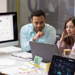 A diverse team of AWS infrastructure experts reviewing a scalable cloud architecture diagram on a large screen, with AWS service icons and upward growth arrows.